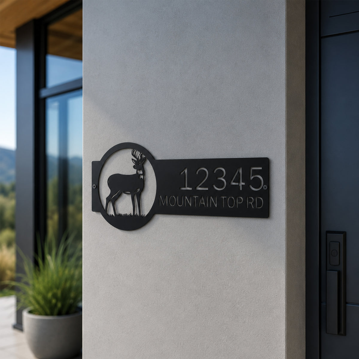 Black personalized deer address plaque mounted on light exterior wall featuring custom house number mountain top road text and wildlife design