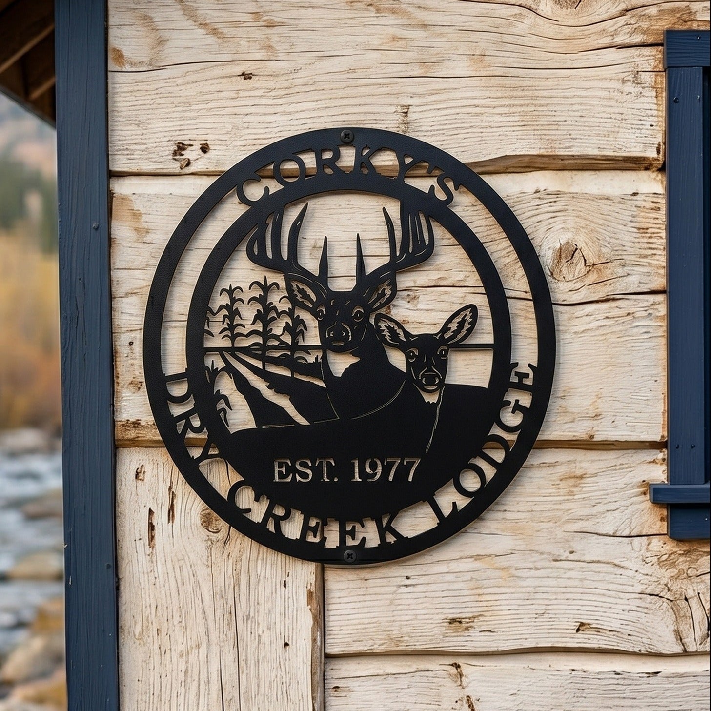 Black Corky’s Dry Creek Lodge metal wall plaque with buck doe and corn field design displayed on rustic cabin siding
