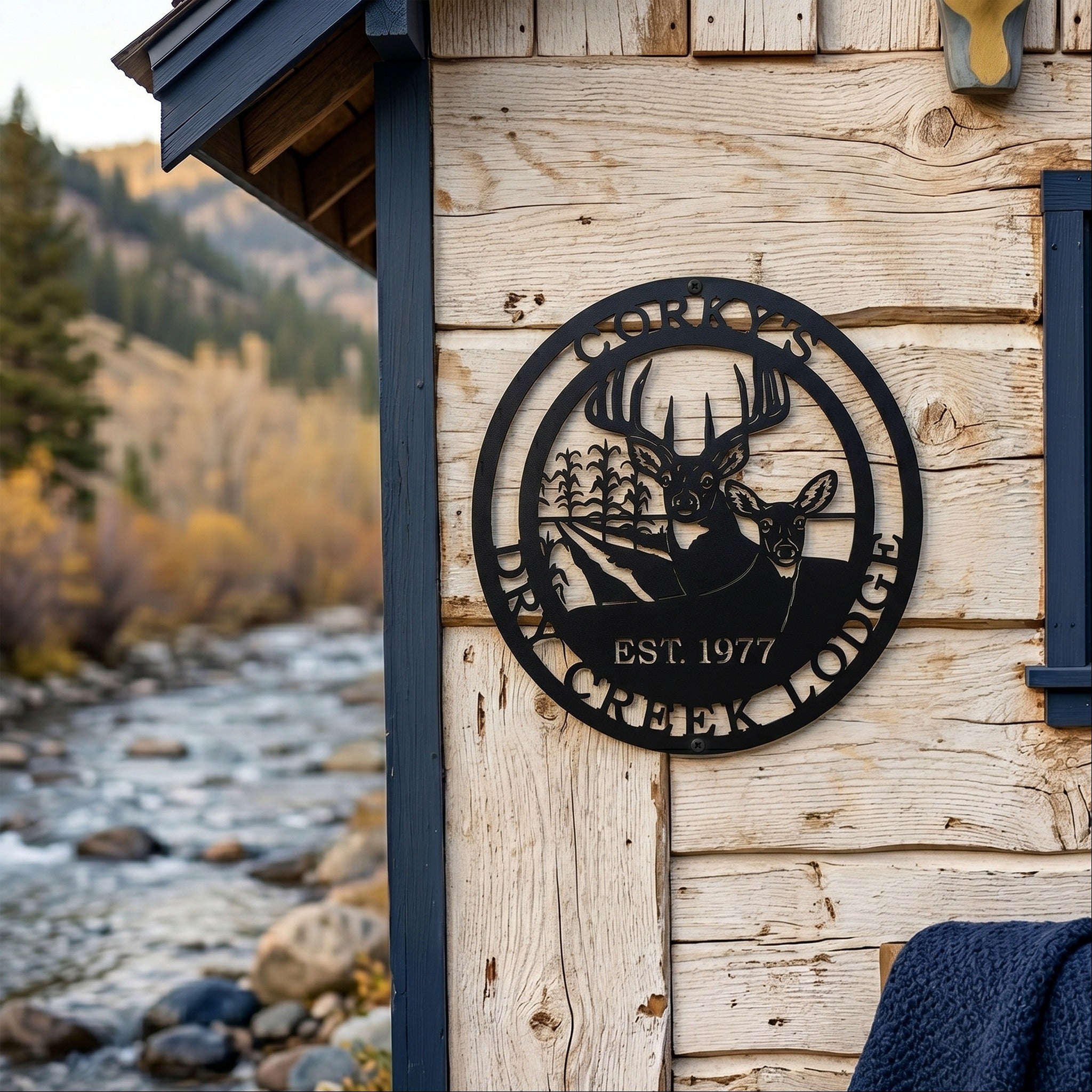 Black Corky’s Dry Creek Lodge metal wall plaque with buck doe and corn field design displayed on rustic cabin siding
