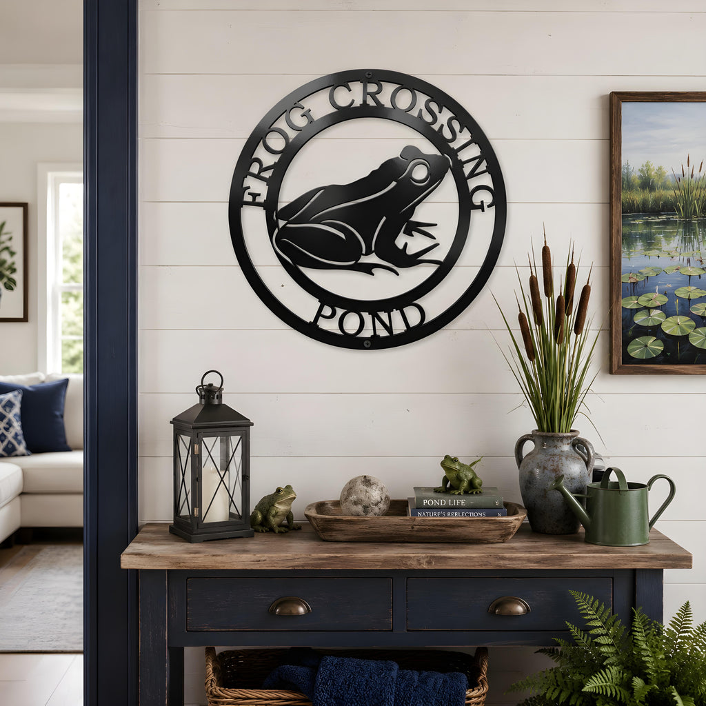 Black frog pond metal wall art displayed above rustic console table with lanterns and pond themed decor