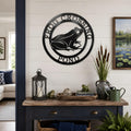 Black frog pond metal wall art displayed above rustic console table with lanterns and pond themed decor