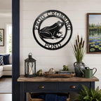 Black frog pond metal wall art displayed above rustic console table with lanterns and pond themed decor