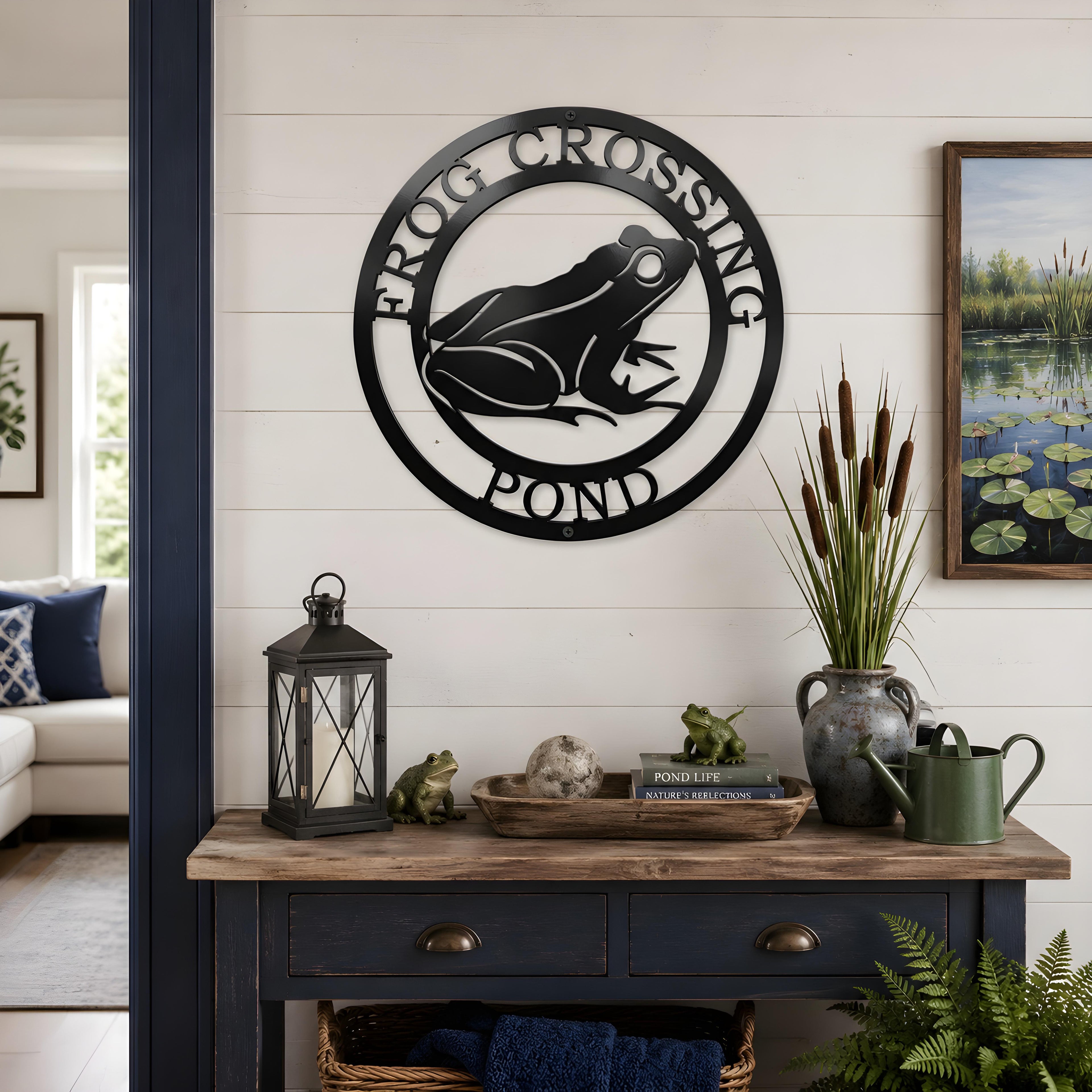 Black frog pond metal wall art displayed above rustic console table with lanterns and pond themed decor