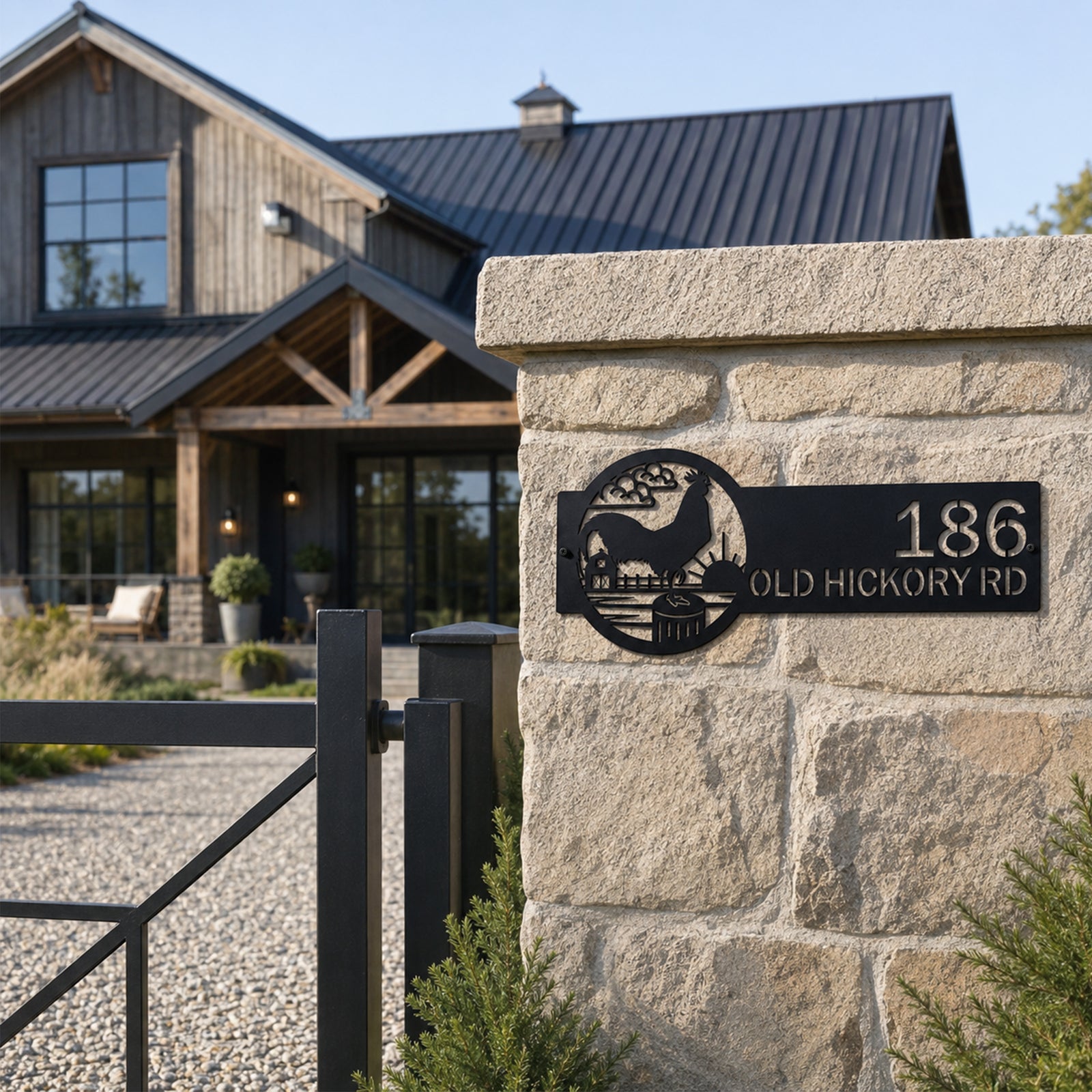 Black rooster farmhouse address plaque attached to stone gate column featuring custom house number and rural barn scene outdoor metal wall decor