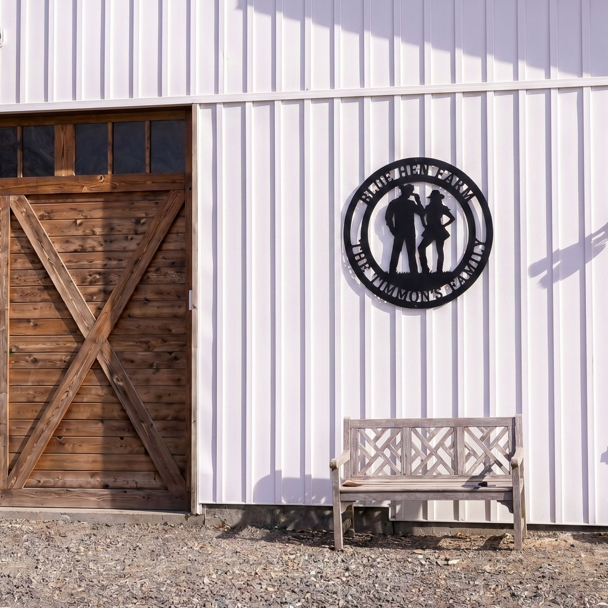 Personalized cowboy and cowgirl metal farm sign mounted on white barn wall beside wooden bench outdoors