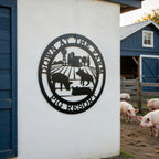 Black pig resort metal wall sign with farm landscape and pig silhouettes displayed beside a wooden barn pen