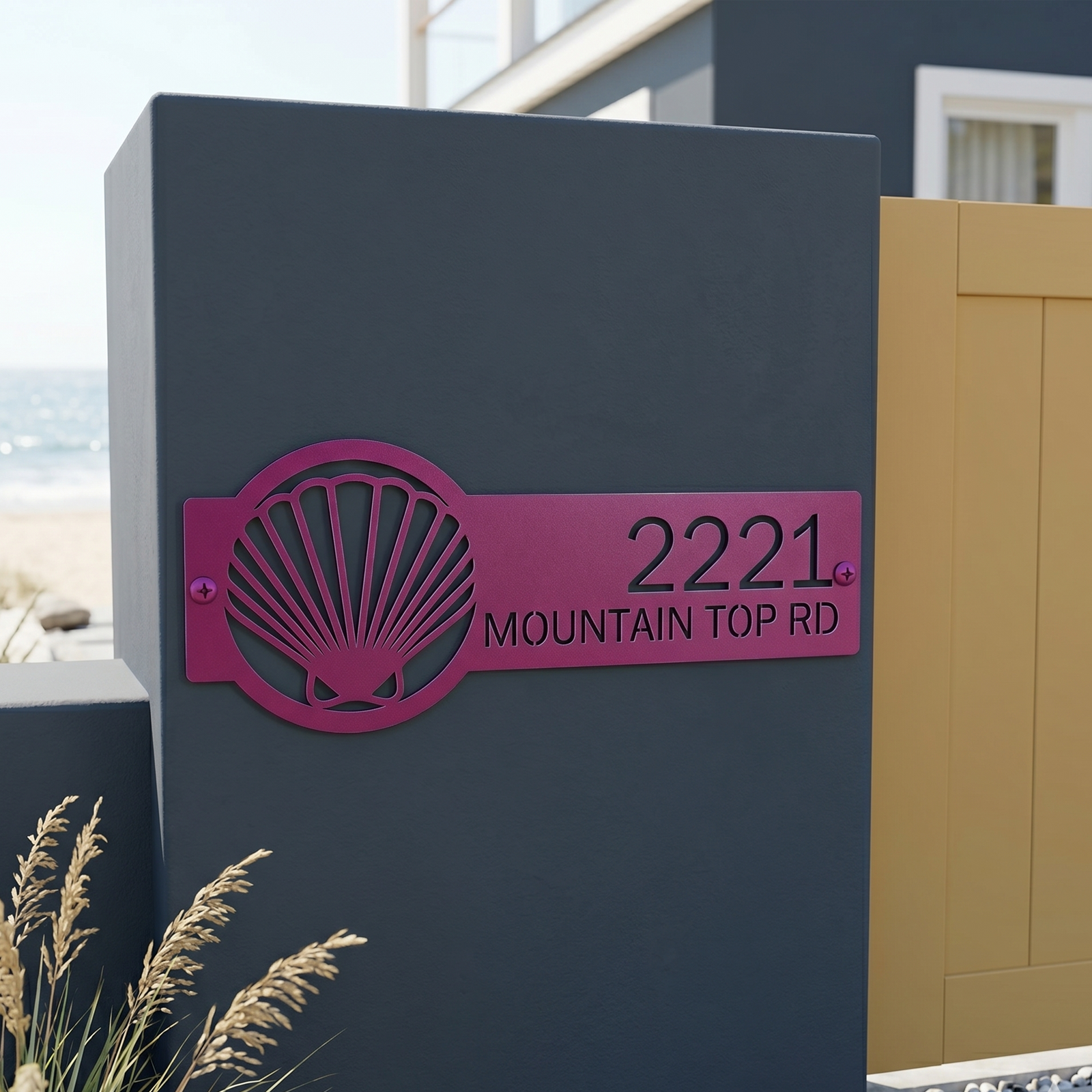 Magenta seashell address sign with house number on coastal entry pillar near beach gate
