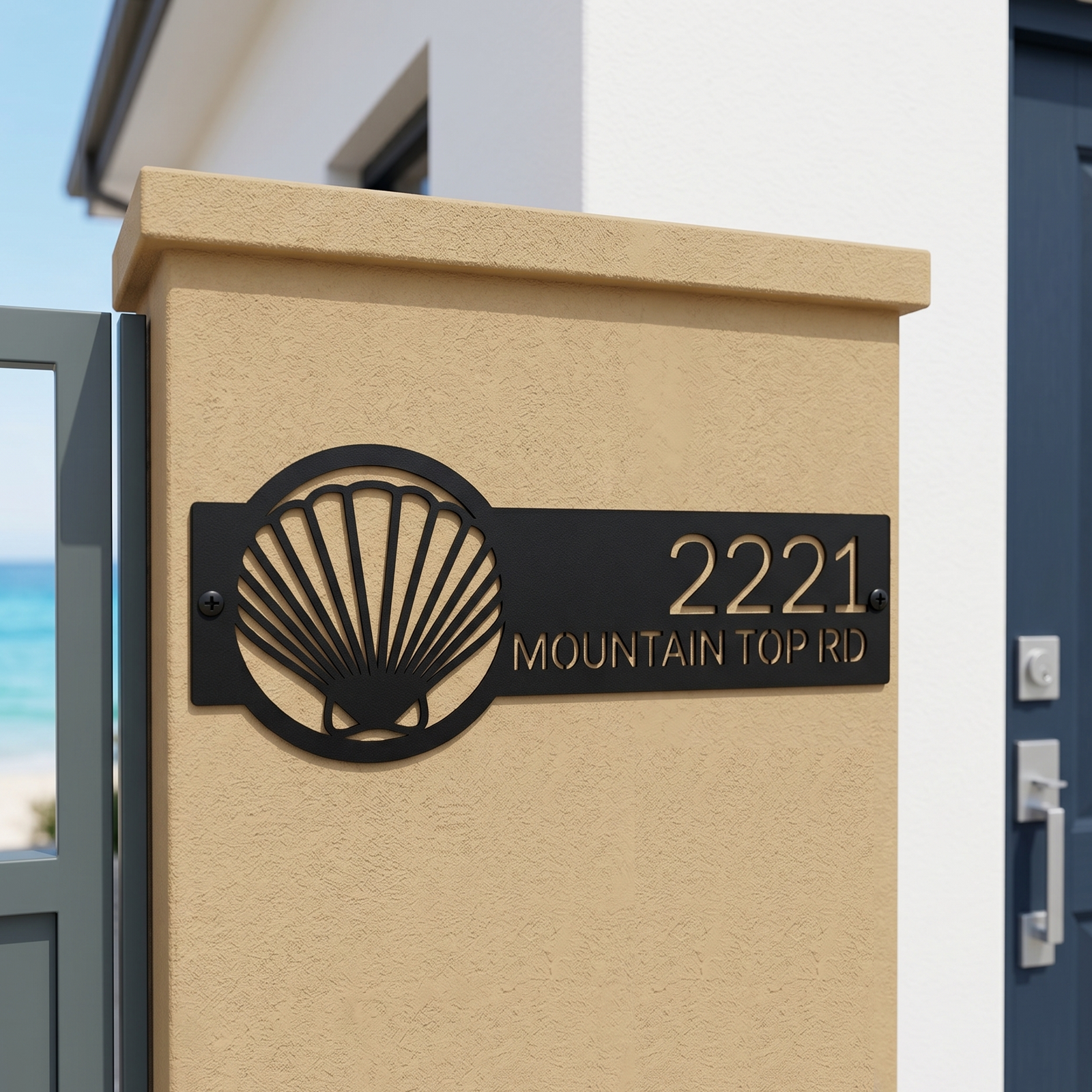 Black seashell address sign with house number on stucco pillar near ocean front entry