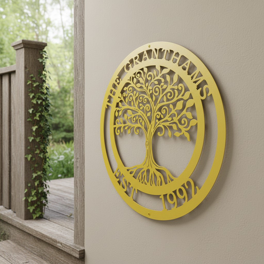 A bright mustard yellow circular metal cutout sign customized with the text "THE GRANTHAMS EST. 1992" around a central tree motif. The piece is hanging on a beige exterior wall column beside a wooden porch railing wrapped in climbing green ivy.