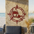 Deep red shark compass metal wall art displayed on a stone patio wall with beach seating and ocean view