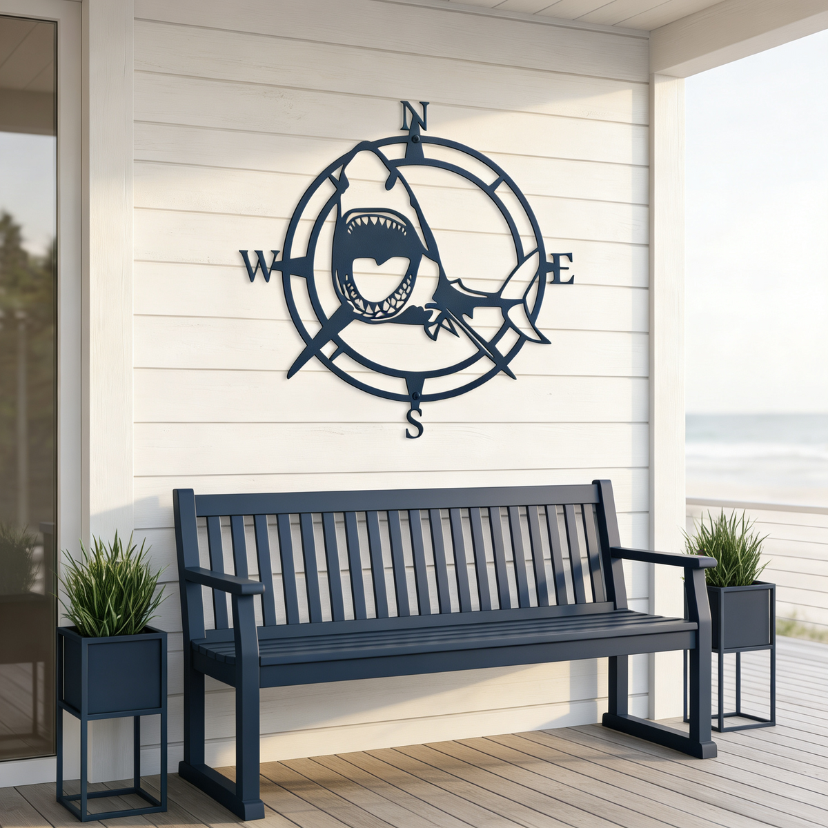 Navy blue shark compass metal wall art mounted above an outdoor bench on a coastal porch with ocean view