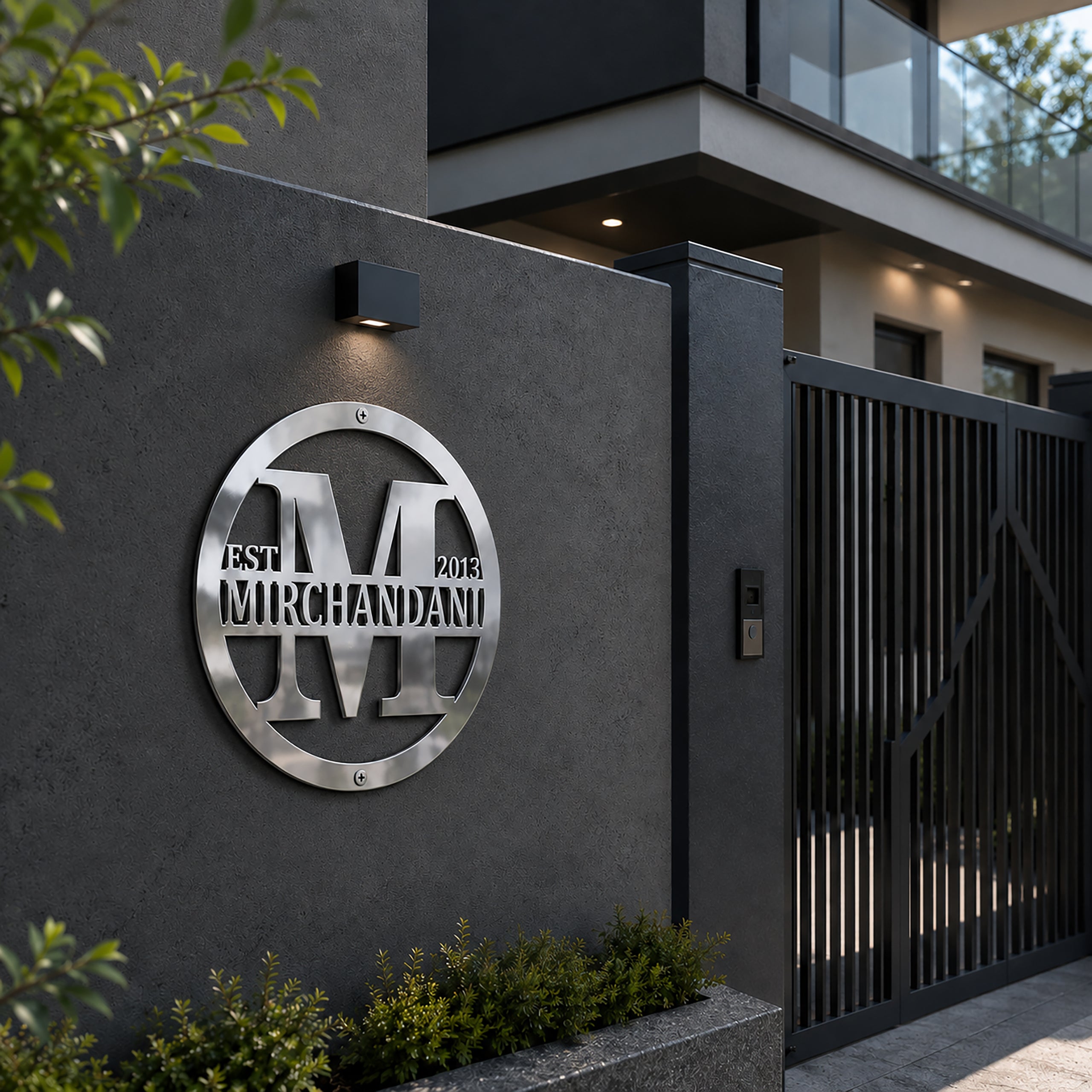 Chrome personalized family name metal sign mounted on a modern exterior wall beside a black gate