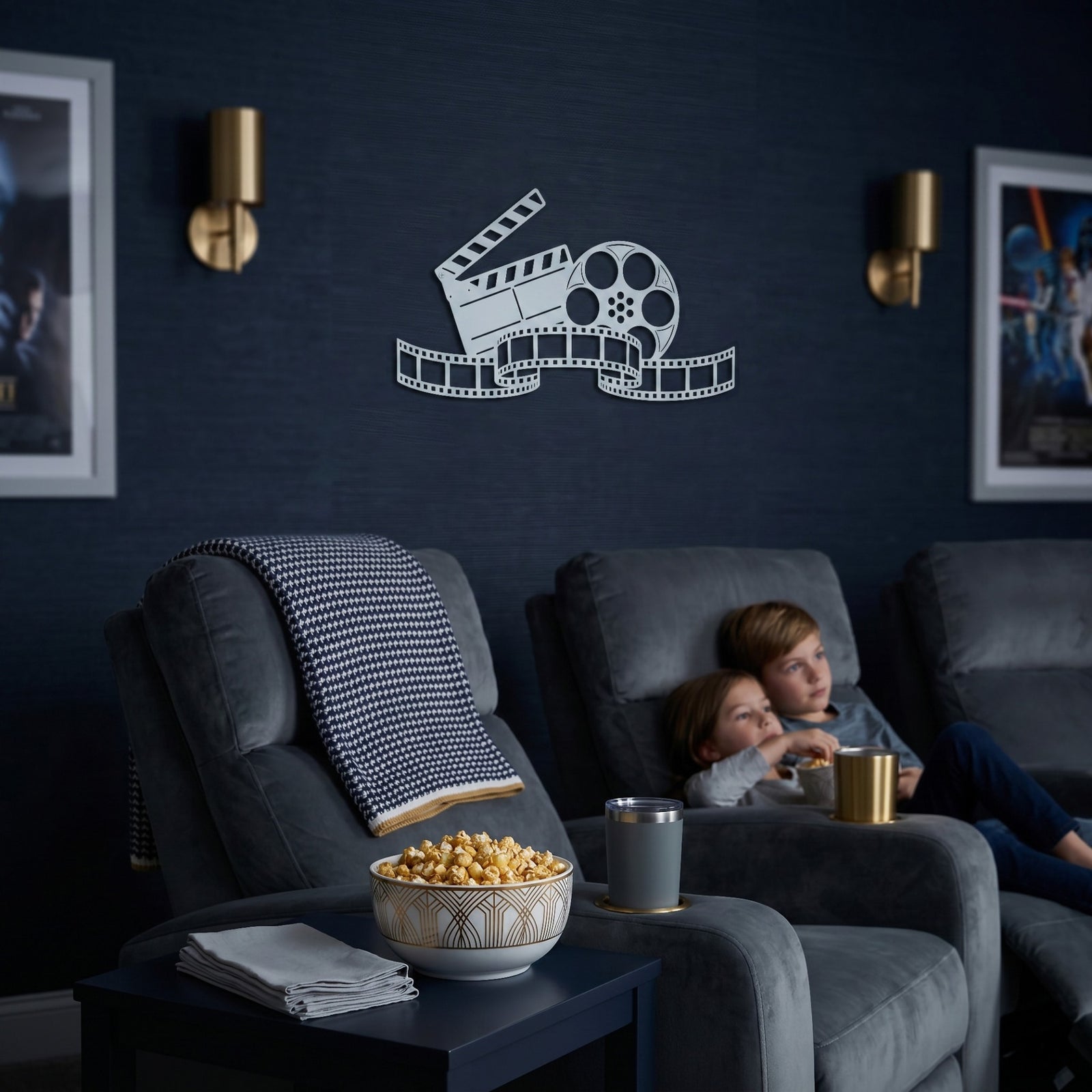 Sky white movie reel and clapperboard metal wall decor displayed in a cozy home theater with reclining seats popcorn and movie posters on dark blue walls