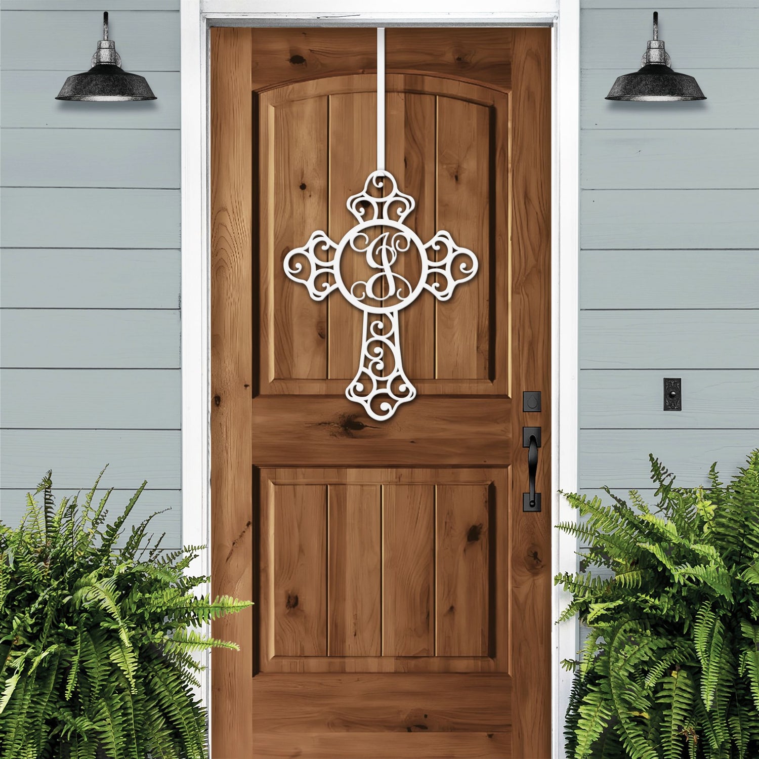 Custom Swirl Monogram Cross Door Sign displayed on a wooden door, featuring a personalized metal cross design for front door decor, showcasing craftsmanship and elegance for indoor and outdoor use.