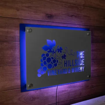 LED backlit 3D metal business logo sign for “The Hillside Vineyards Winery,” featuring a blue design and decorative elements, displayed on a wooden background.