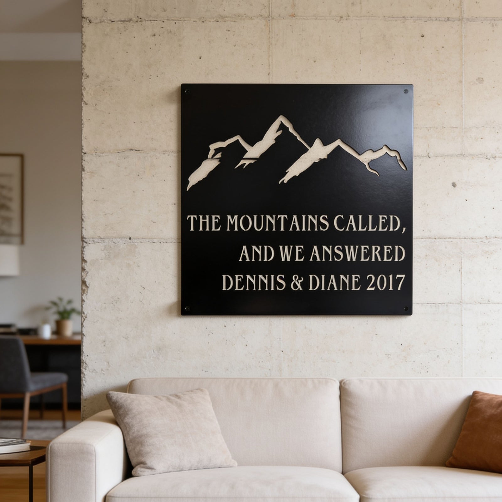Sky white mountain metal sign with personalized names and date mounted on an outdoor patio wall overlooking a scenic mountain landscape.