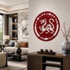A vibrant ruby red circular metal heritage plaque featuring an intricate traditional dragon centerpiece and the words "THE ZHANG FAMILY EST. 2000" cut out along the top and bottom arches. It is hung in a modern living room setting over a wooden cabinet styled with an Asian ceramic vase.