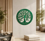 An emerald green circular metal sign showcasing a leafy tree with birds and the cut-out words "IN THE CIRCLE OF LIFE, YOU SHOULD NEVER TAKE MORE THAN YOU GIVE" around its rim. The sign hangs on a cream wall above stacked white meditation cushions in a serene room with potted palms and vertical wood paneling.