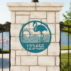 Turquoise flamingo metal address sign with sunset waves and number 123456 on stone pillar