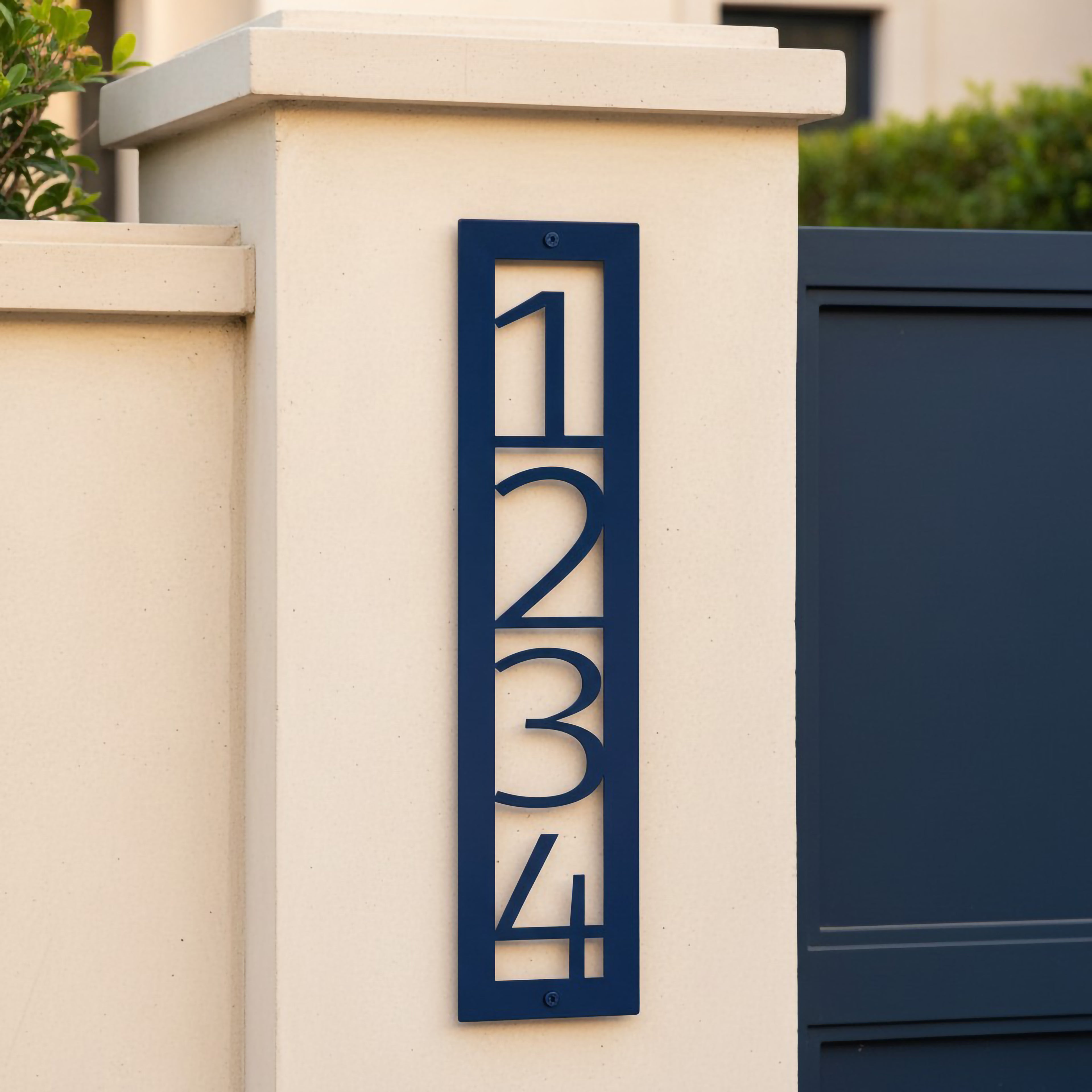 Navy blue vertical metal house number sign 1234 displayed on a white front gate pillar with matching blue gate background