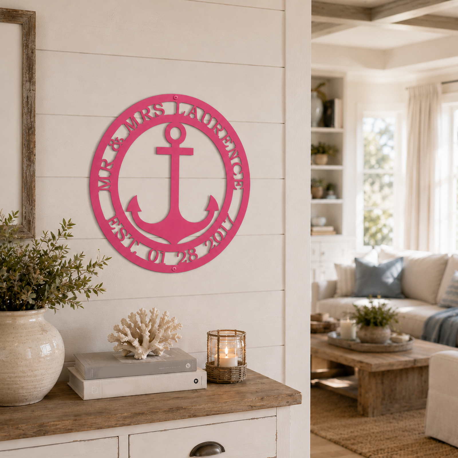 Hot pink finish of the custom circular anchor wedding sign with personalized family surname hung on a white shiplap wall above a white entryway dresser.