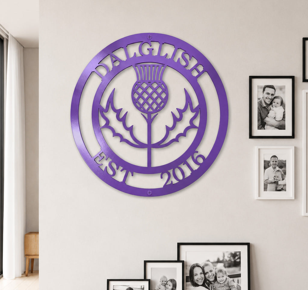 Bright lilac purple finish of the custom personalized Scottish thistle metal sign styled on a neutral-toned wall above a dark wood entryway credenza.