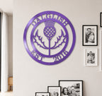 Bright lilac purple finish of the custom personalized Scottish thistle metal sign styled on a neutral-toned wall above a dark wood entryway credenza.