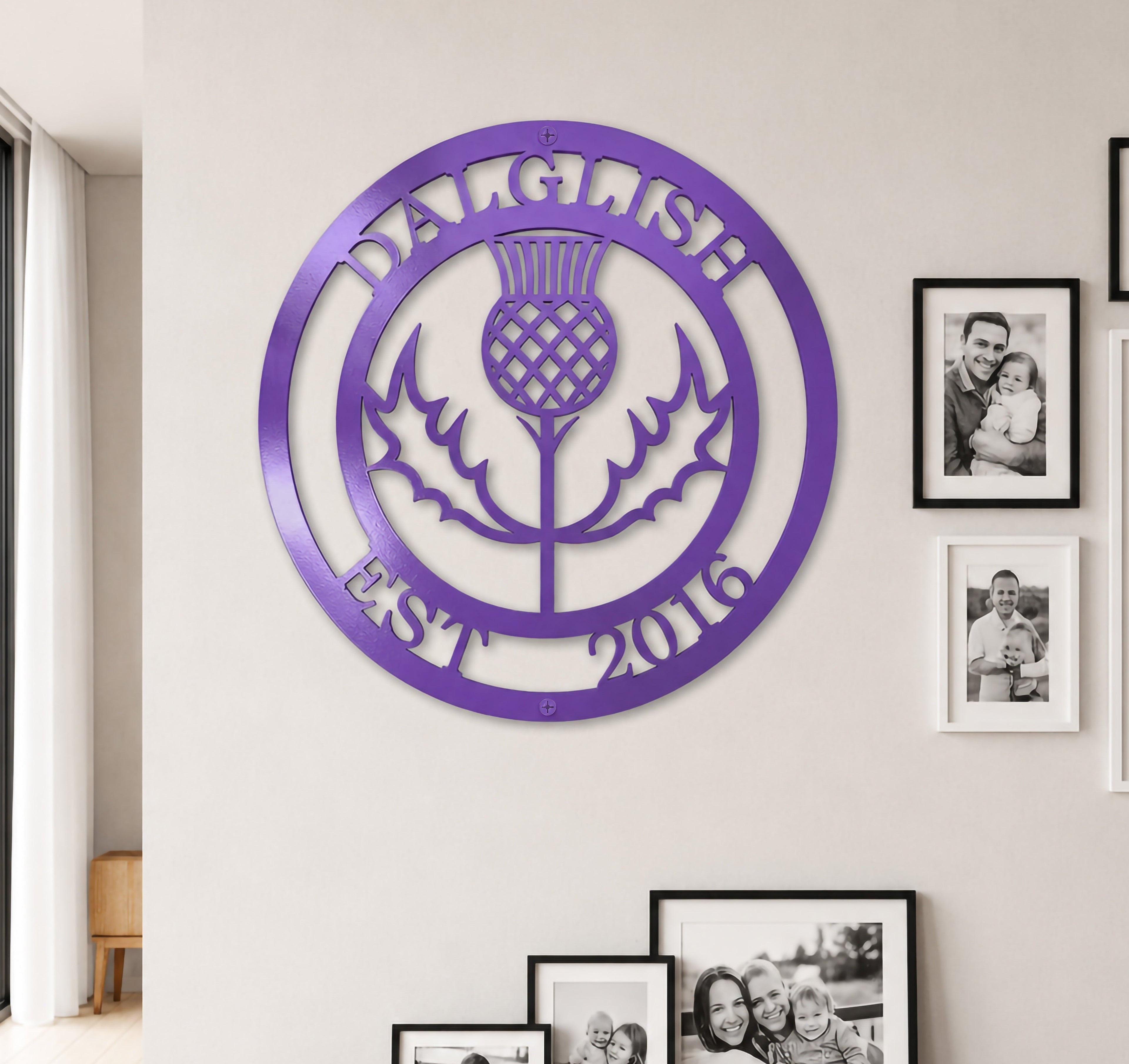Bright lilac purple finish of the custom personalized Scottish thistle metal sign styled on a neutral-toned wall above a dark wood entryway credenza.