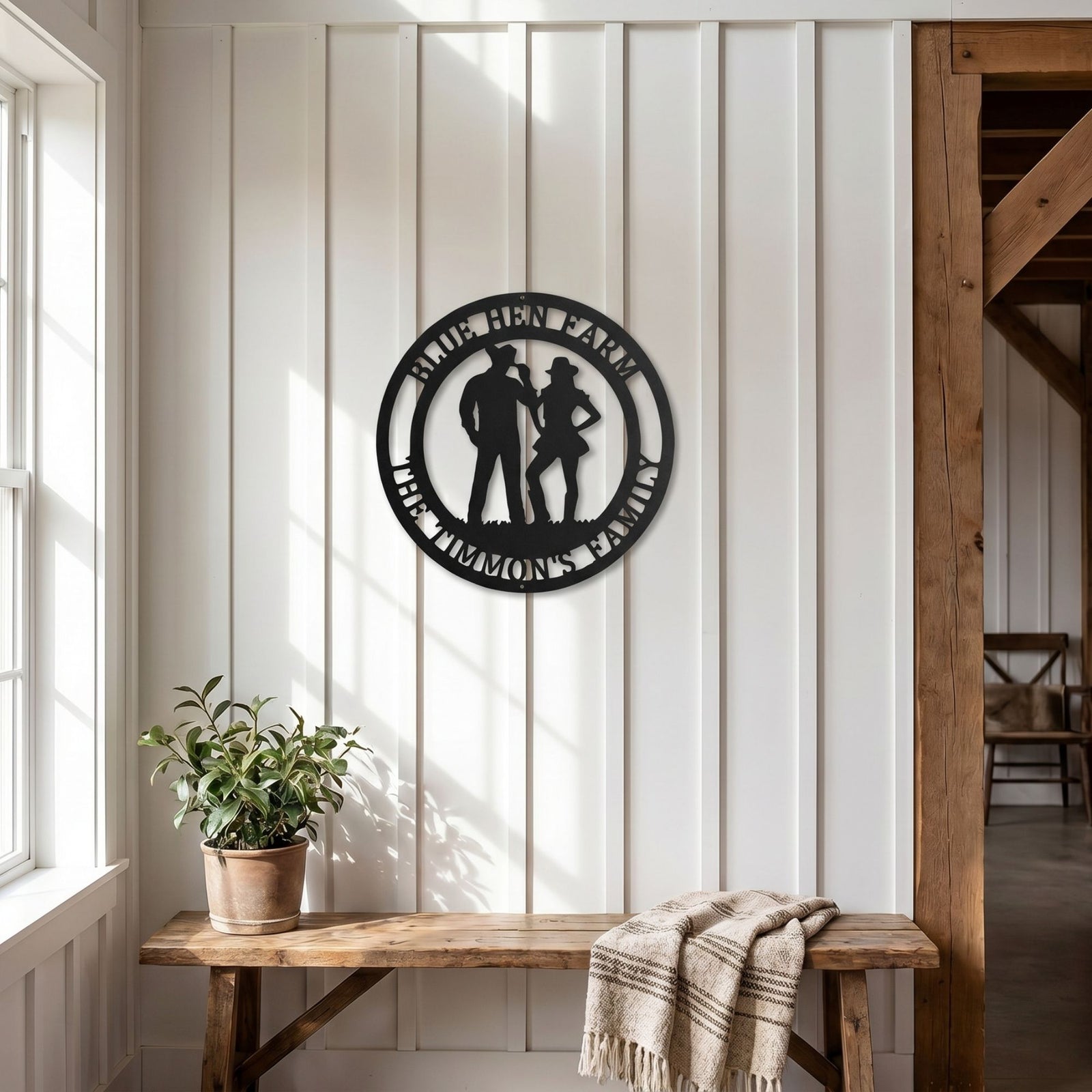Personalized western metal farm sign with cowboy couple silhouette mounted on white shiplap wall above rustic bench