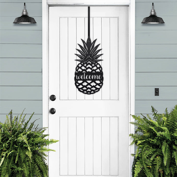 White pineapple welcome metal door sign displayed on black front door for classic porch welcome decor
