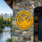 Golden yellow Corky’s Dry Creek Lodge metal wall sign with buck and doe design displayed on stone lodge exterior by mountain creek