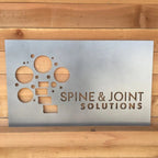 Custom LED office and storefront metal sign featuring “Spine & Joint Solutions” text, precision-cut for professional branding, illuminated business signage, and outdoor display.