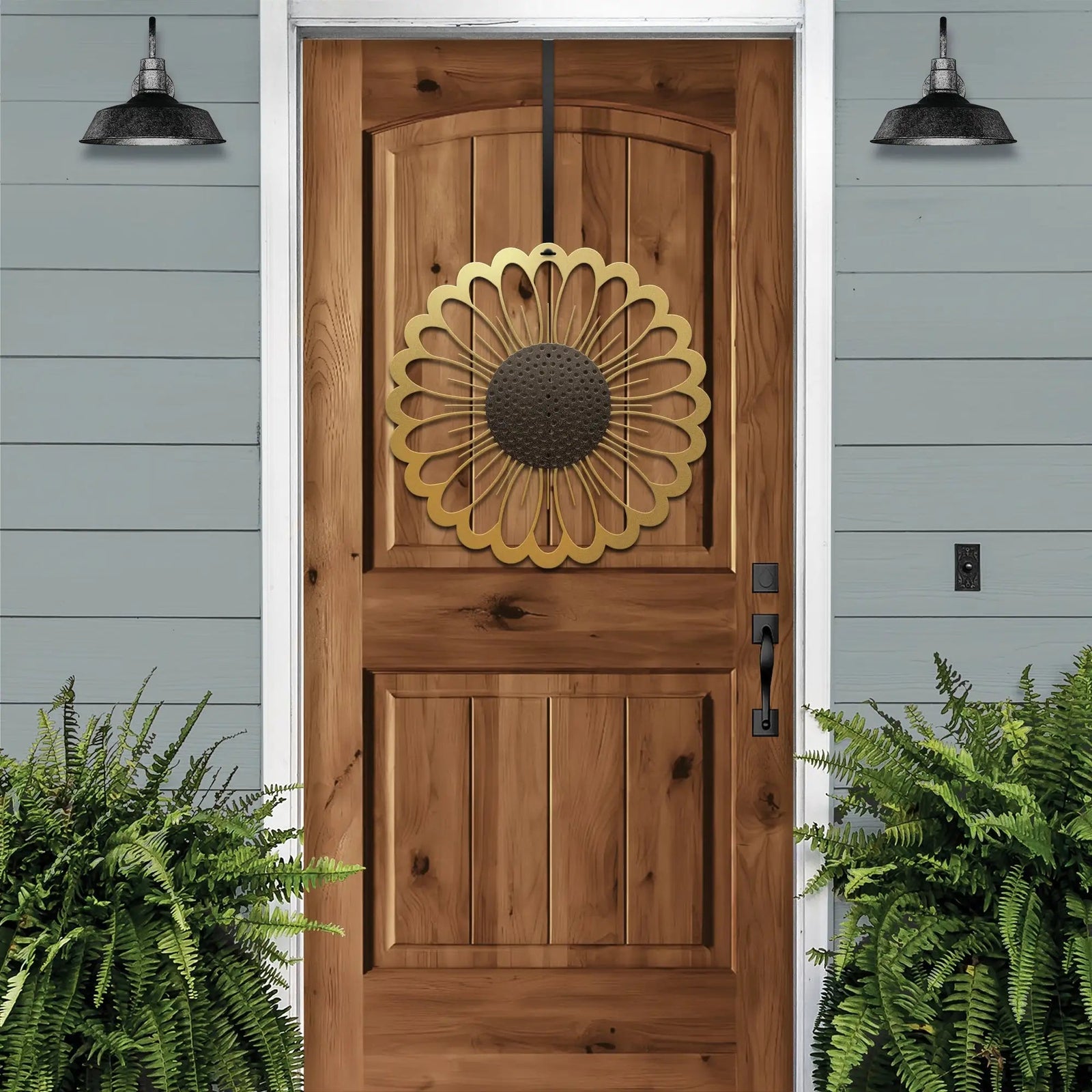 Sunflower metal wreath on wooden front door, bright floral circular design, light blue house exterior, handcrafted outdoor metal decor, modern entryway art