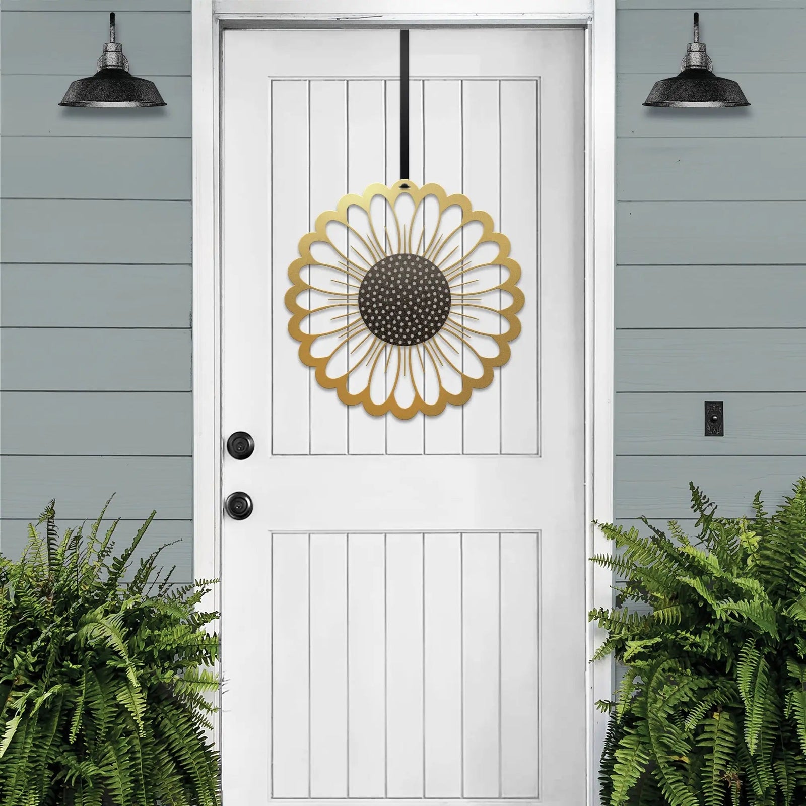 Gold circular sunflower metal wreath on white door, gray wooden wall exterior, bright entryway decor, handcrafted outdoor metal sign, modern home design