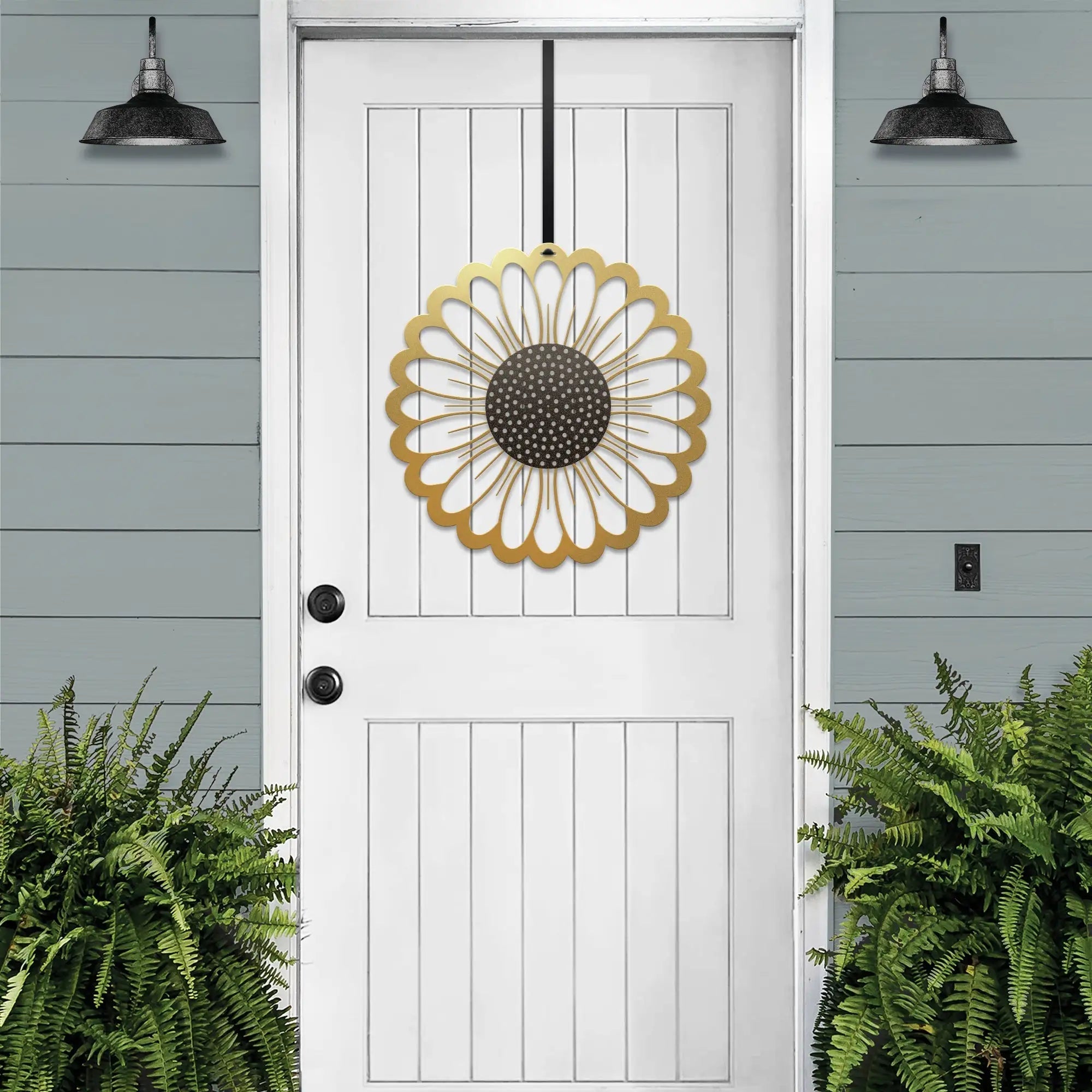 Gold circular sunflower metal wreath on white door, gray wooden wall exterior, bright entryway decor, handcrafted outdoor metal sign, modern home design