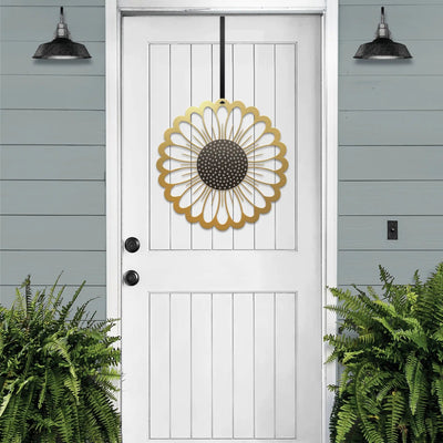 Gold circular sunflower metal wreath on white door, gray wooden wall exterior, bright entryway decor, handcrafted outdoor metal sign, modern home design