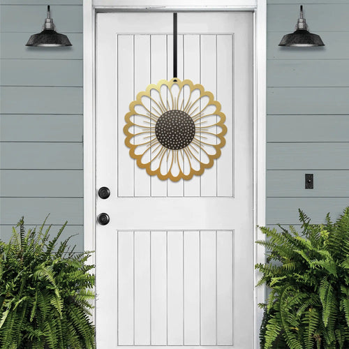 Gold circular sunflower metal wreath on white door, gray wooden wall exterior, bright entryway decor, handcrafted outdoor metal sign, modern home design