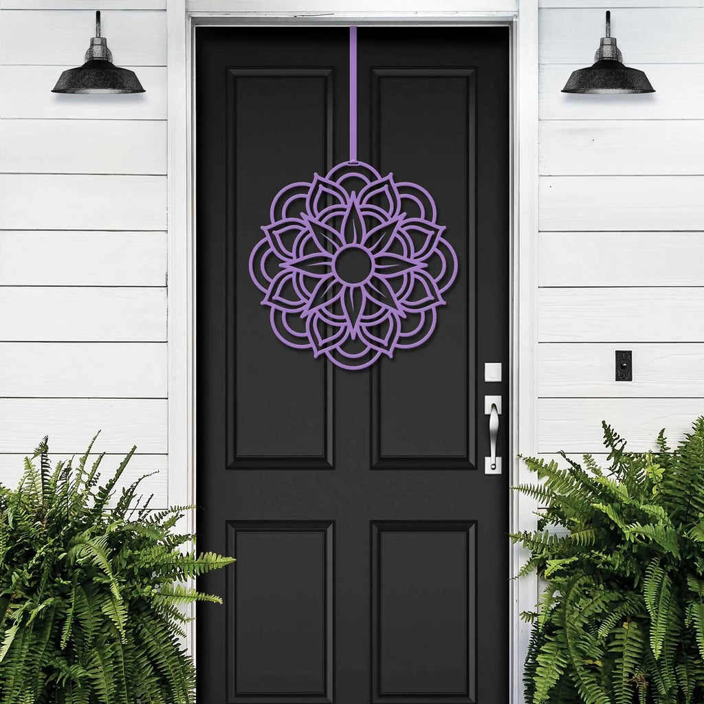 Purple cascading floral wreath on black door, elegant door decor for events, white wall exterior with lush green plants, garden home art