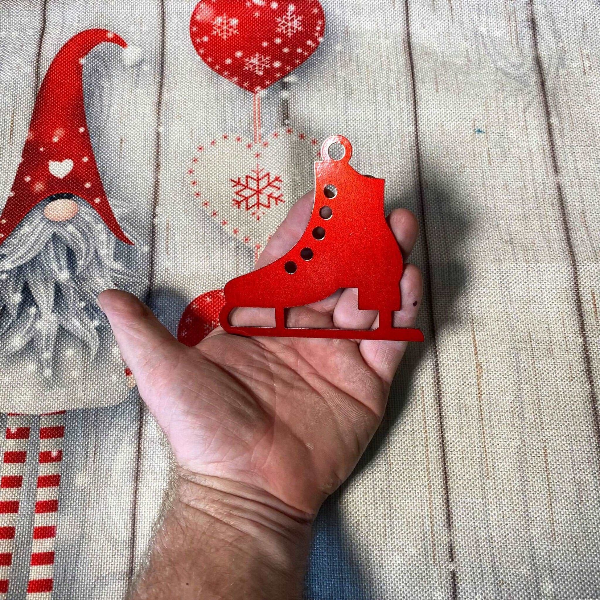 Hand holding a red ice skate Christmas ornament with festive holiday fabric background, seasonal decoration for Christmas trees and winter décor