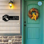 Custom teal corn monogram address sign with house numbers, personalized outdoor plaque, mounted on wooden wall by front door with wreath and light fixture
