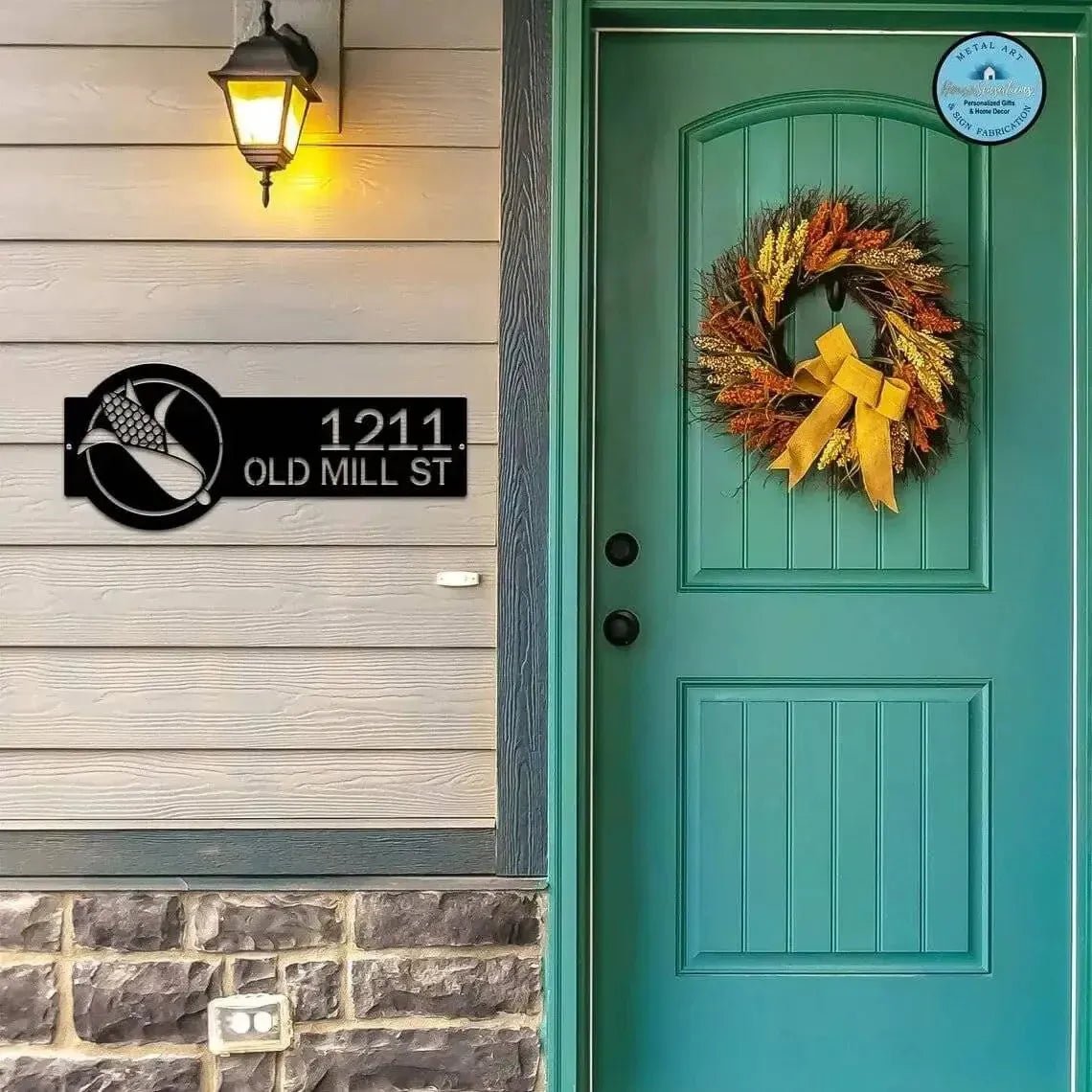 Custom teal corn monogram address sign with house numbers, personalized outdoor plaque, mounted on wooden wall by front door with wreath and light fixture