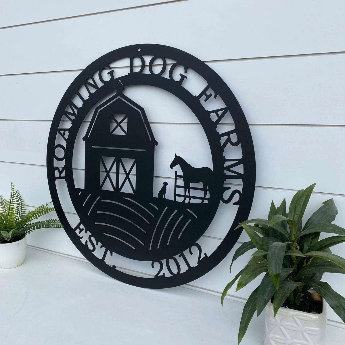 Custom barn dog horse ranch metal sign for farmhouse décor, side view of personalized “Roaming Dog Farms” plaque on white wooden background.