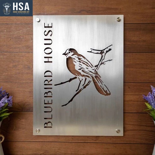 Metal sign with bluebird illustration and 'Bluebird House' text on a wooden background