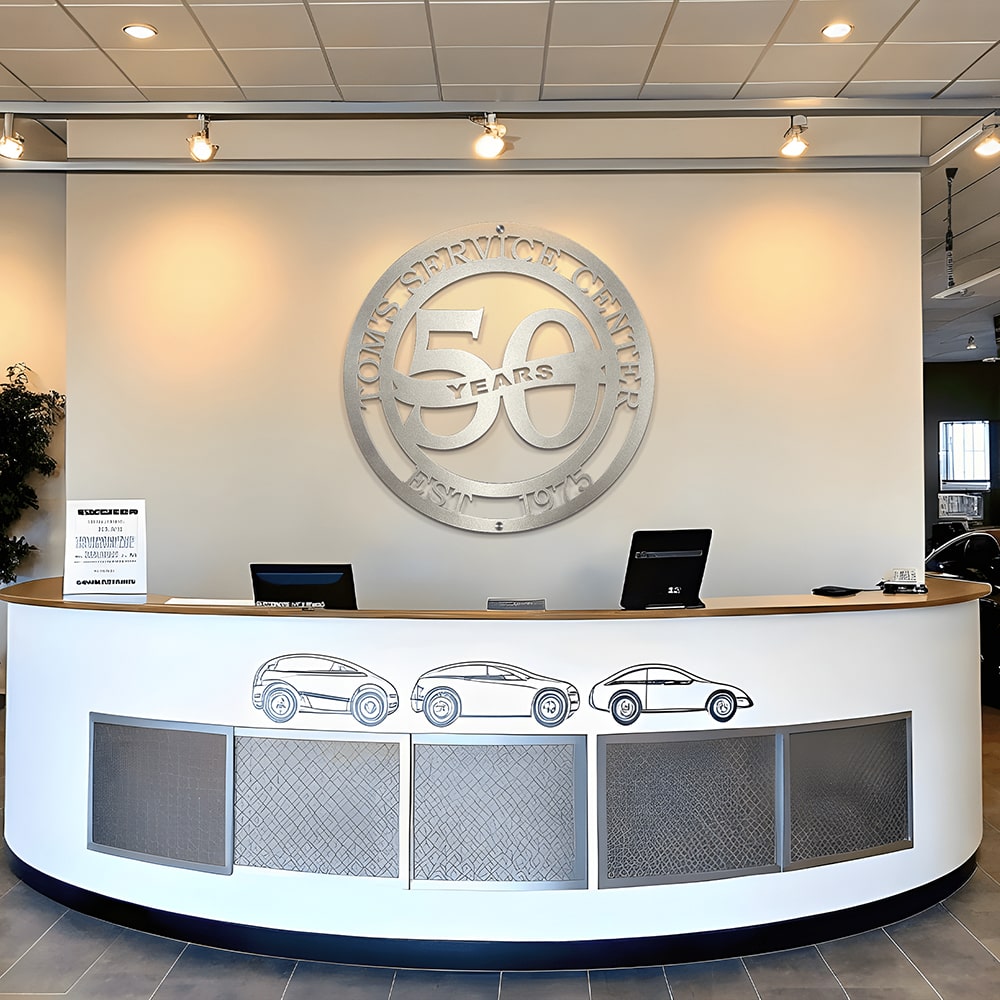 Custom business anniversary metal sign reading “50 Years” with year of establishment, displayed on reception desk in car dealership, HouseSensationsArt