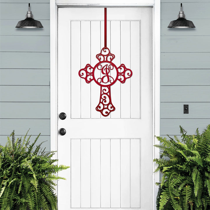 Red cross monogram metal door wreath displayed on a white door