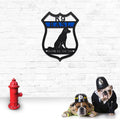 Decorative metal wall art featuring a dog silhouette and text mounted on a white brick wall, with two dogs in front wearing police and firefighter hats, creating a charming and themed décor scene.
