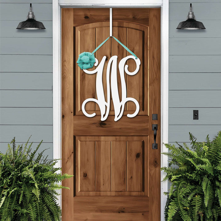 White personalized metal initial door wreath displayed on a wood front door