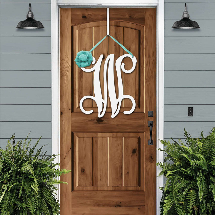 White personalized metal initial door wreath displayed on a wood front door