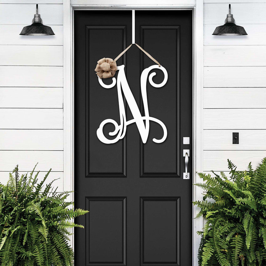 White personalized metal initial door wreath displayed on a black front door