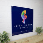 Metal logo sign featuring a colorful bird design mounted on a white brick wall with a blue background, highlighting vibrant colors and durable craftsmanship.